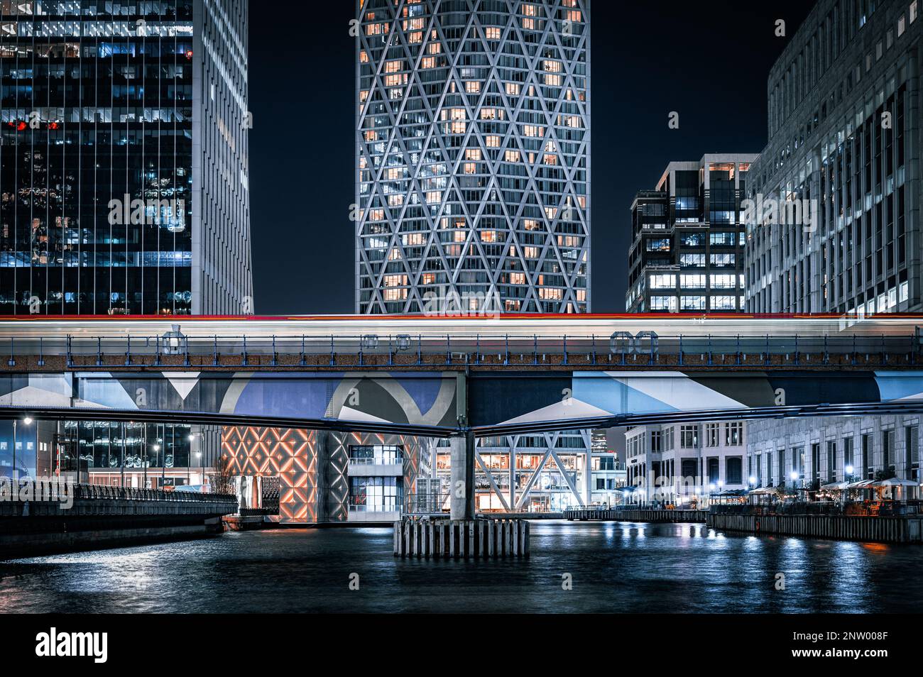 Lunga esposizione del treno DLR di Canary Wharf che attraversa un ponte, visto dal punto di vista di Canary Wharf, Londra. Foto Stock