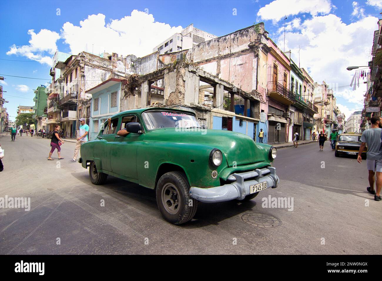 Auto d'epoca verde ad un incrocio a l'Avana, Cuba, con un vecchio edificio sullo sfondo. Foto Stock