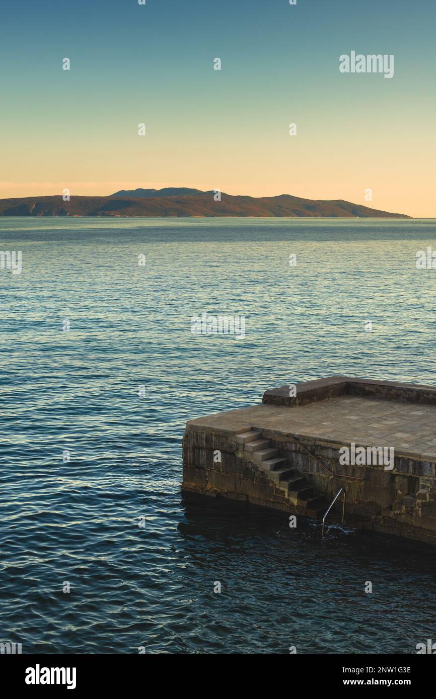 Scale in cemento e molo in pietra nella città di Lovran, nel golfo del Quarnero del mare Adriatico al tramonto Foto Stock