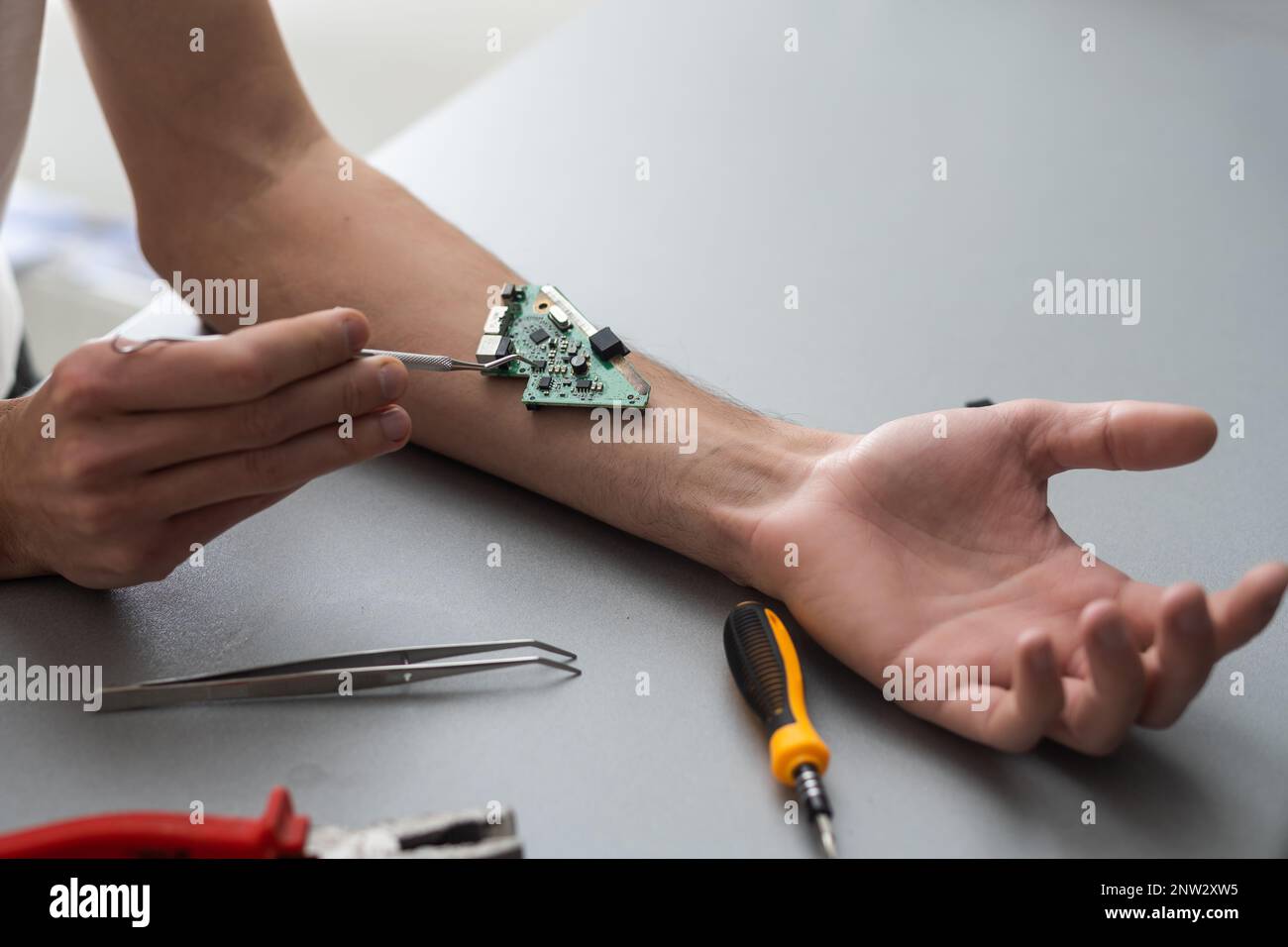 Concetto del braccio del robot. L'uomo mostra una mano biomeccanica protesica. Guy ripara la mano con l'attrezzo. Bioingegneria, transumanesimo, biohacking, cyborg umano Foto Stock