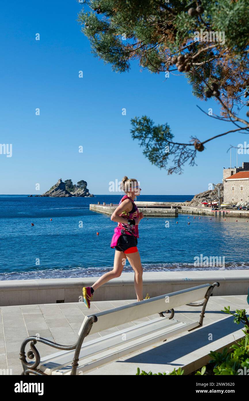 Donna che corre lungo il lungomare di Petrovac, Montenegro Foto Stock