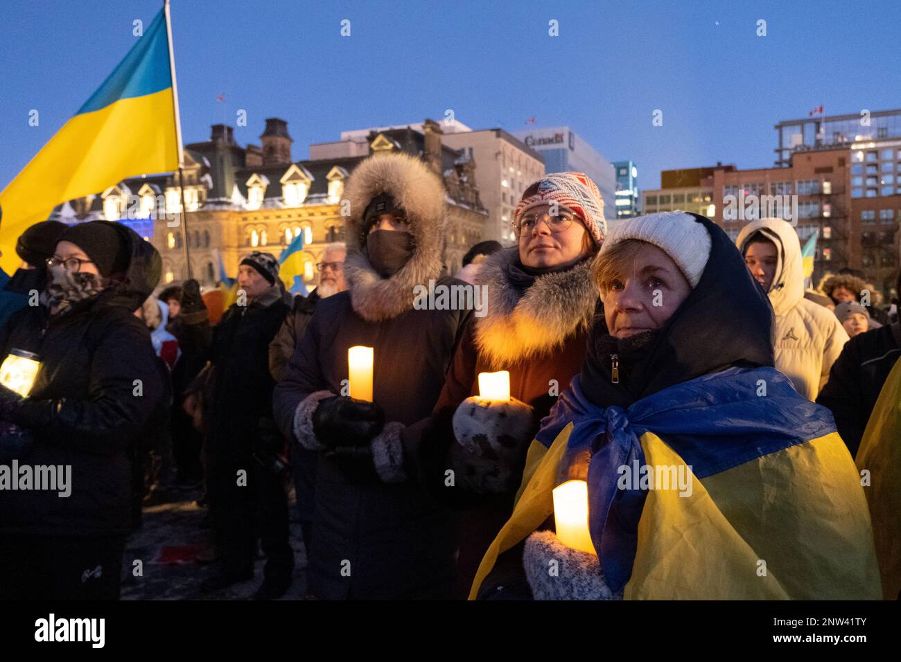Un gruppo di persone si è riunito ciascuno con una candela accesa e una bandiera Ucraina, in uno spettacolo di solidarietà durante una protesta Foto Stock