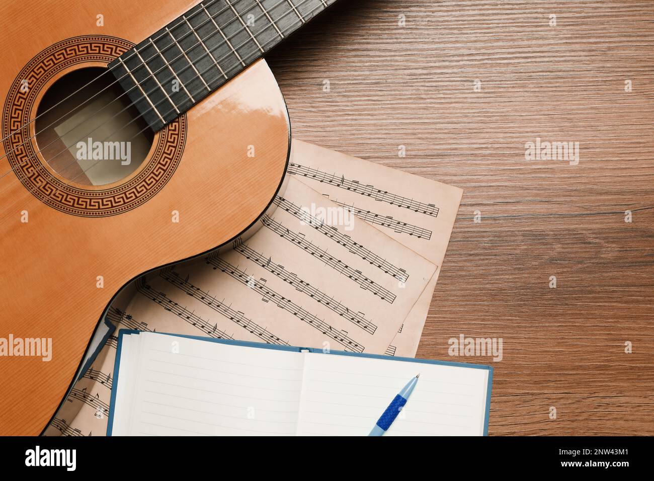 Composizione con chitarra e note musicali su tavolo in legno, piatto Foto Stock