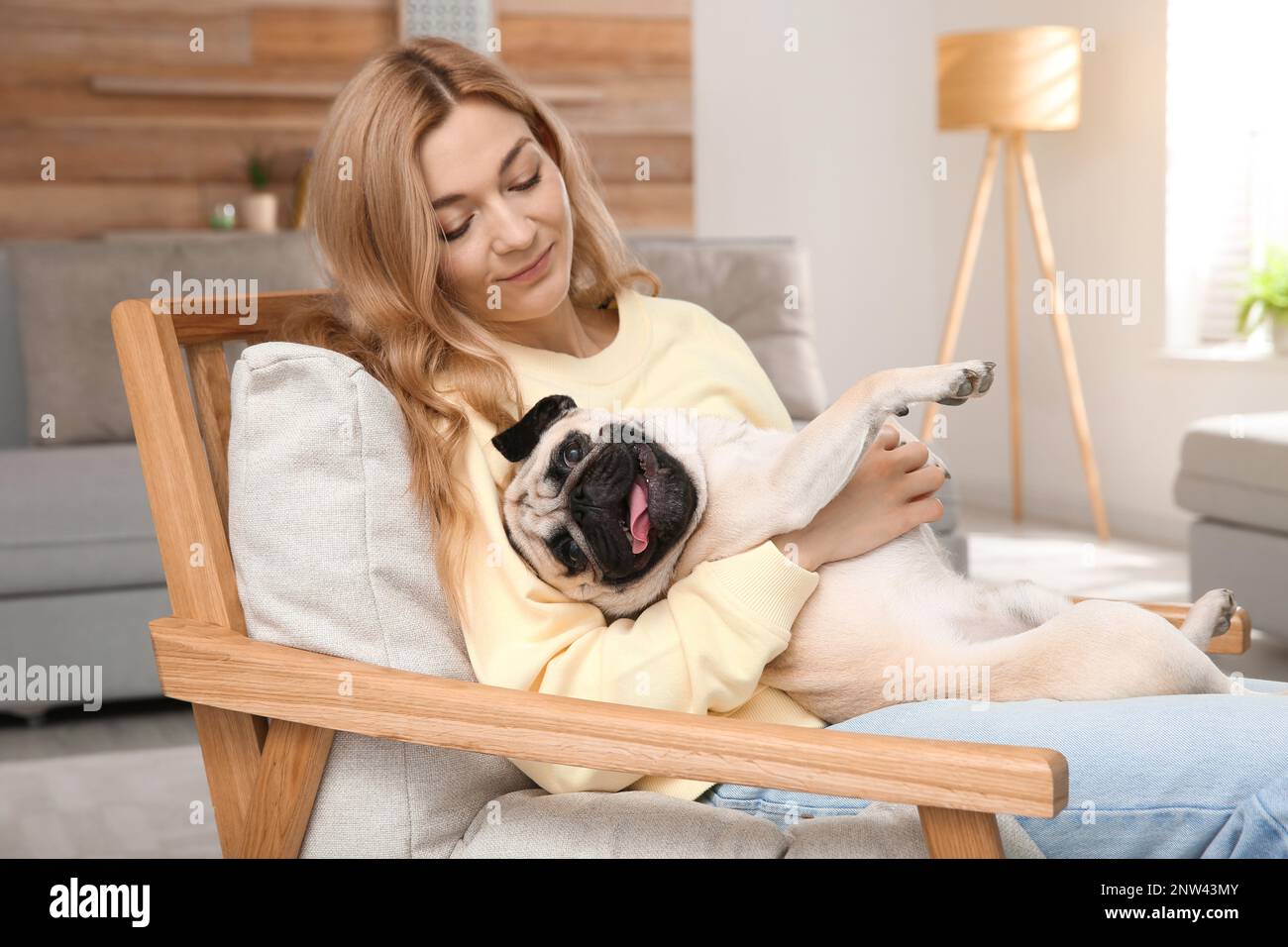 Donna con carino cane pug a casa. Adozione animale Foto Stock