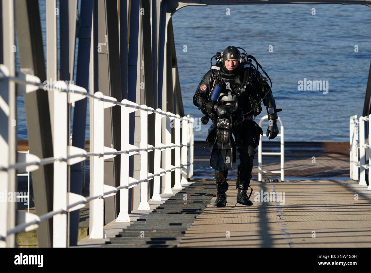 Amburgo, Germania. 28th Feb, 2023. Un sommozzatore di polizia torna al suo veicolo dopo essersi tuffato nell'Elba. Da martedì mattina, la polizia sta cercando un ragazzo che si dice sia caduto nell'Elba al terminal dei traghetti Bubendey-Ufer di Amburgo. Testimoni oculari avevano cercato di far uscire dall'acqua il bambino di età apparentemente compresa tra i dieci e i dodici anni, ma senza successo. Quindi, secondo le relazioni degli aiutanti, il ragazzo andò sotto e non resuscitò. La polizia sta ora cercando il ragazzo con subacquei, ufficiali a terra ed elicotteri. Credit: Marcus Brandt/dpa/Alamy Live News Foto Stock