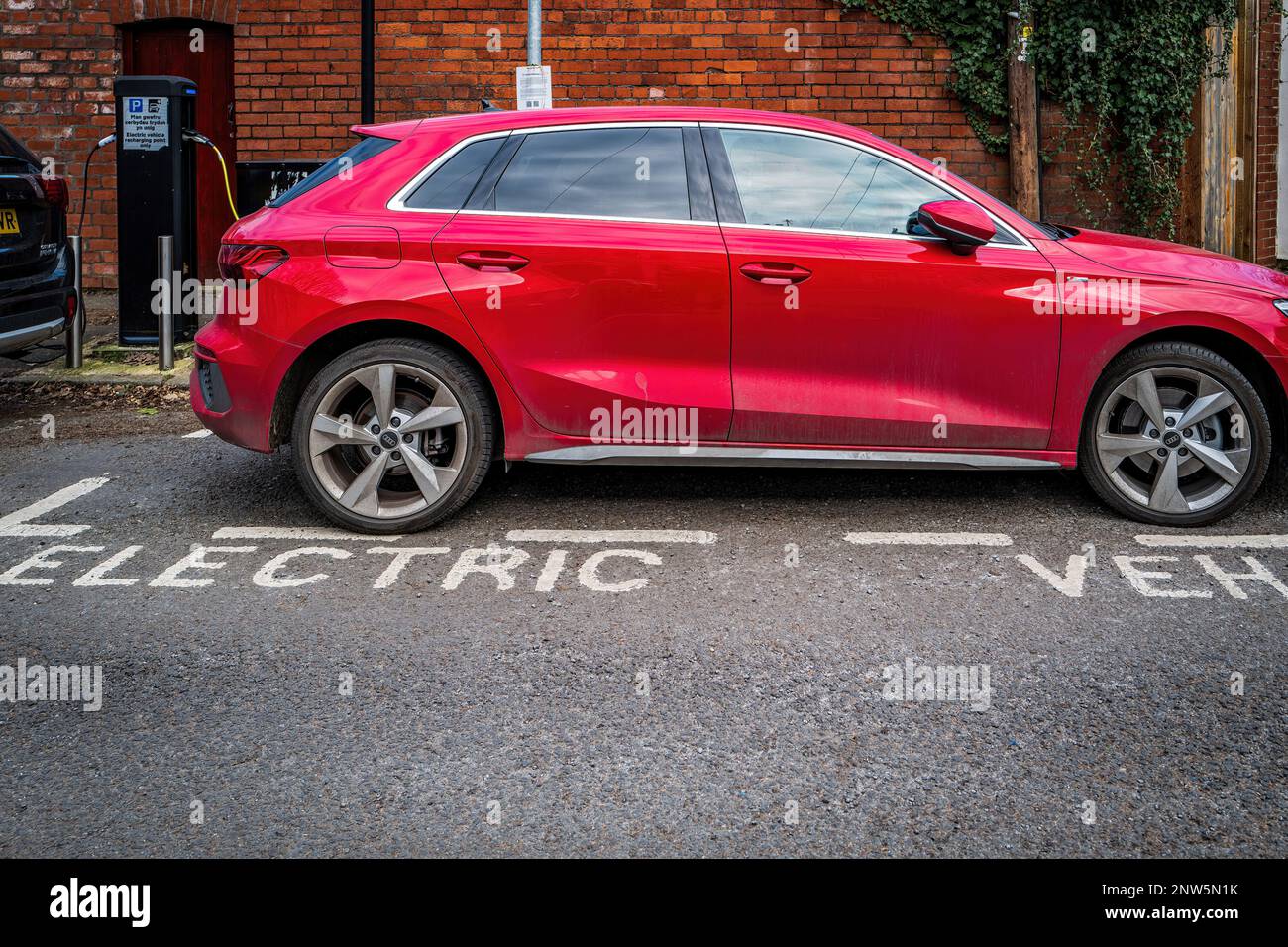 Il veicolo elettrico (EV) viene caricato in un punto di ricarica in una strada suburbana a Cardiff, Galles, Regno Unito. Elettrificazione dei trasporti. Concetto. Foto Stock