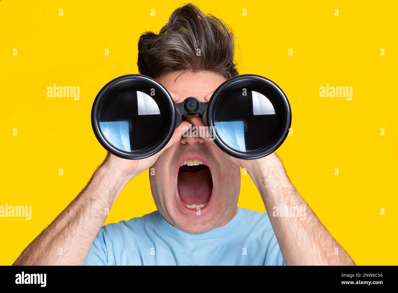 Un uomo cartoon con una t-shirt blu e uno sfondo giallo che guarda attraverso il binocolo con un'espressione sorpresa Foto Stock