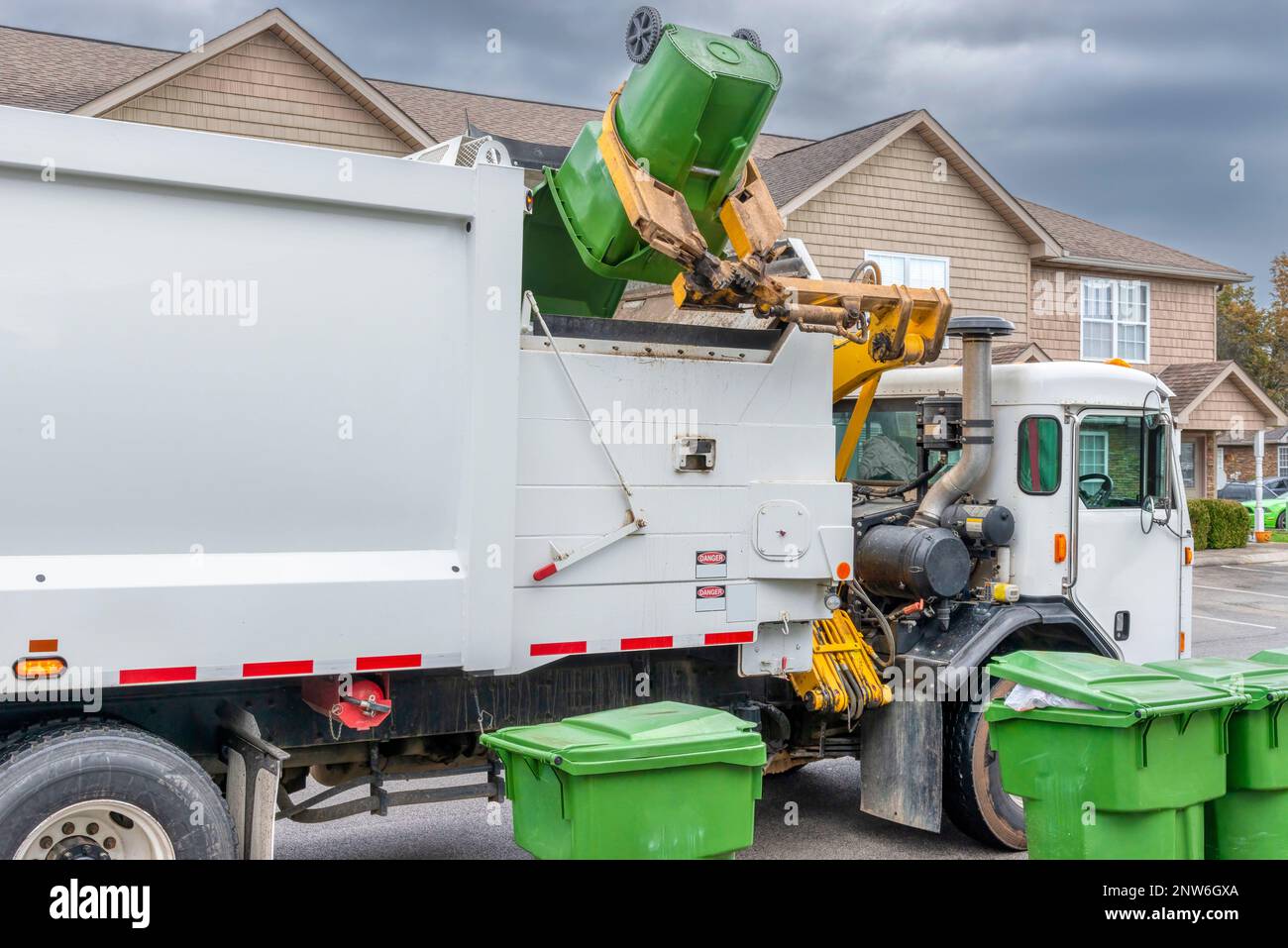 Colpo orizzontale del braccio meccanico su un moderno camion di rifiuti che scarica la spazzatura senza aiuto. Foto Stock