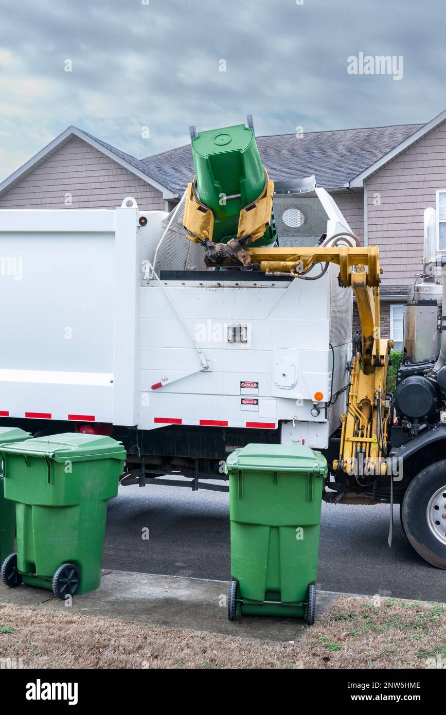 Colpo verticale di un camion di rifiuti meccanizzato che scarica i rifiuti dal barile residenziale. Foto Stock