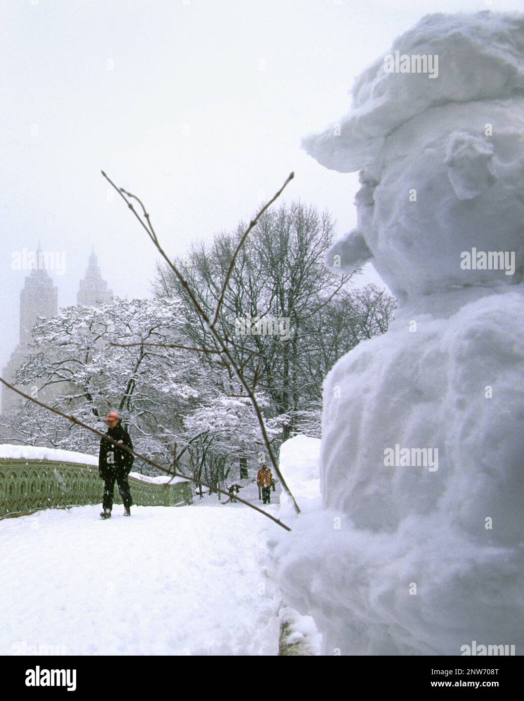 Bow Bridge Central Park New York neve. Pupazzo di neve. Inverno tempesta di neve paesaggio urbano. Tempo gelido. Ragazza che attraversa la passerella pedonale. STATI UNITI Foto Stock