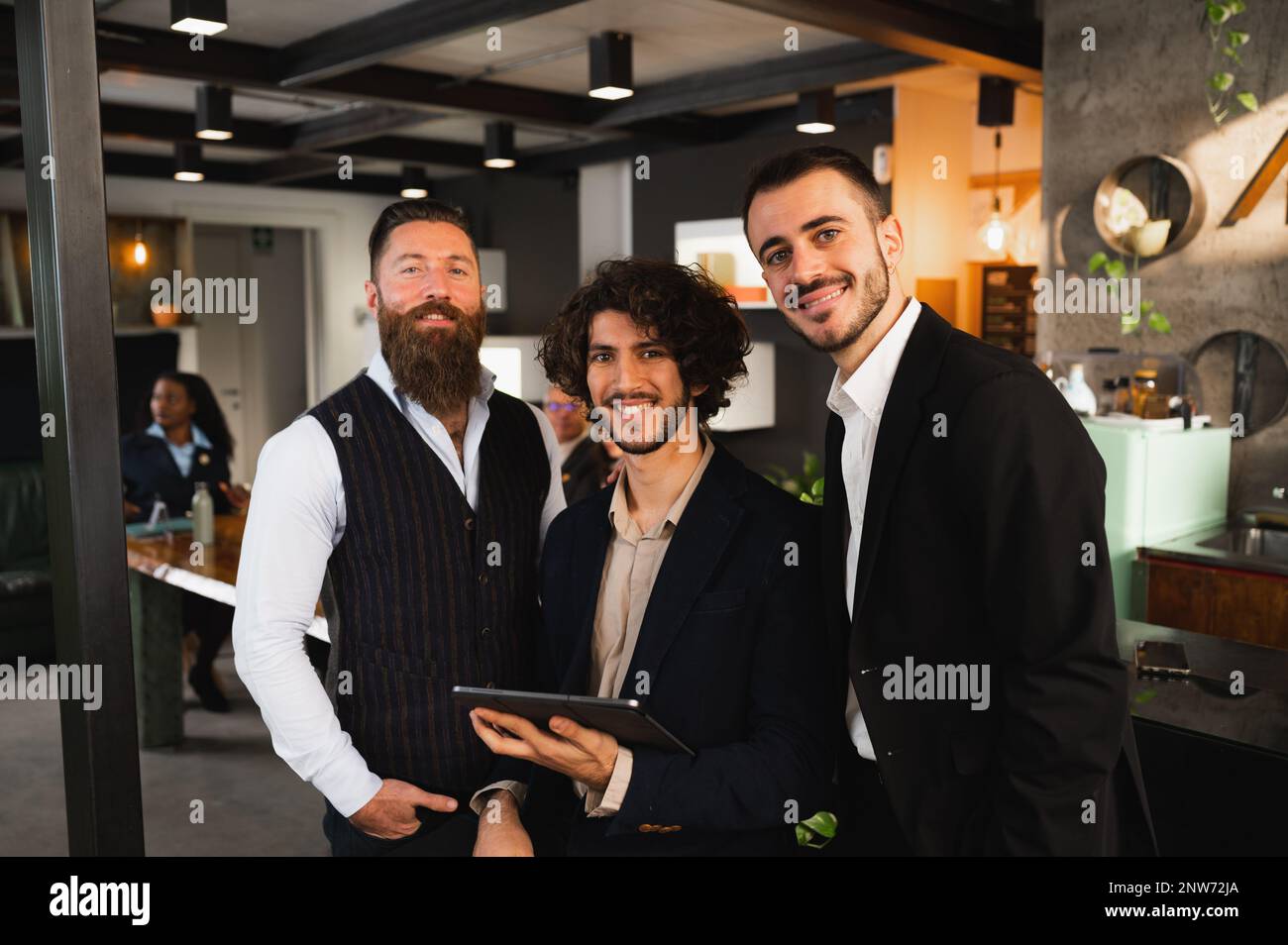 Ritratto di tre uomini hipster che guardano la fotocamera sorridente. Uomini d'affari sul luogo di lavoro. Foto Stock