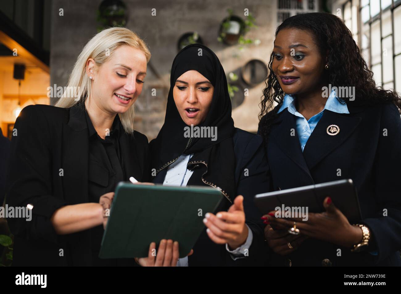 Gruppo di tre donne che utilizzano un tablet e discutono del lavoro Foto Stock