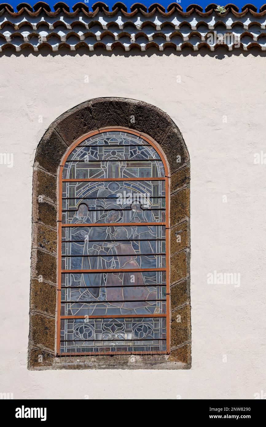 File di tradizionali piastrelle a botte incorniciano una vetrata decorata a incasso presso la Chiesa dell'Immacolata Concezione a Tenerife Foto Stock