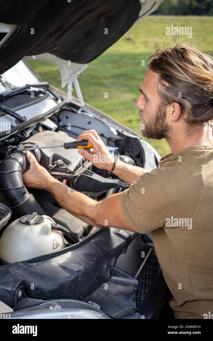 Uomo che ripara un furgone all'aperto Foto Stock