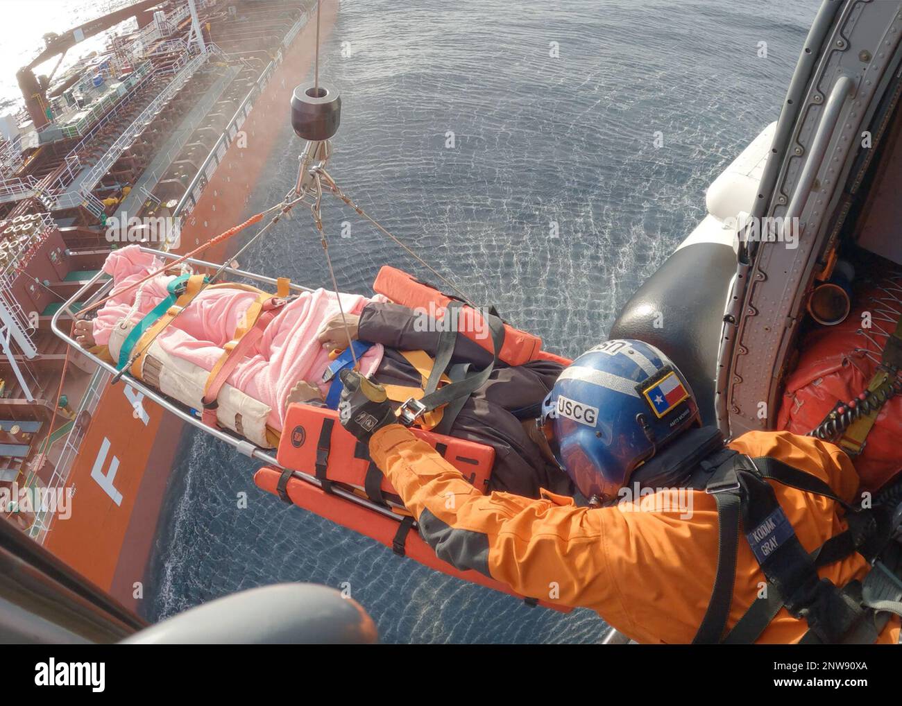 Coast Guard Petty Officer 1st Class Alex Morris, un tecnico meccanico dell'aviazione, salta un uomo di 48 anni in una Air Station Kodiak MH-60 Jayhawk elicottero 220 miglia a sud di Dutch Harbor, Alaska, 11 gennaio 2023. L'equipaggio dell'elicottero MH-60 Jayhawk sollevò il paziente dalla nave container FPMC 33 di 550 piedi e lo trasportò in sicurezza a Cold Bay per un trasferimento ala a ala con il personale LifeMed Alaska che trasportò il paziente a un livello superiore di assistenza medica. STATI UNITI Guardia costiera foto di Scott Kellerman. Foto Stock