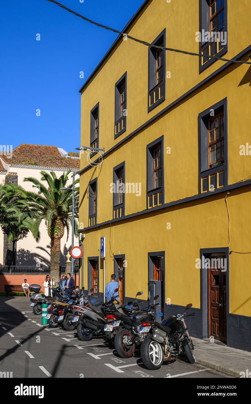 Una fila di motociclette parcheggiate da un edificio giallo brillante ad Antigua Calle San Fructuoso, la Laguna, Tenerife Foto Stock