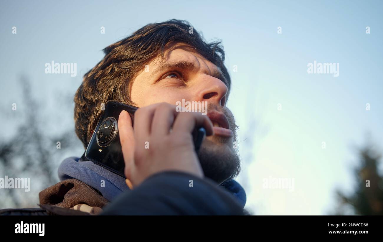 Giovane uomo mettere il telefono all'orecchio e parlare con qualcuno all'aperto Bottom Shot Foto Stock