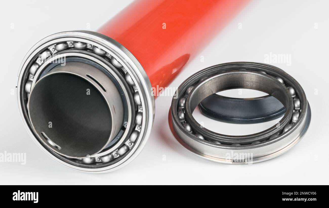 Cuscinetto a sfere a fila singola in acciaio con tamburo di stampa in metallo rosso su sfondo bianco. Elemento volvente sul rullo di pressione cavo dall'unità di fusione della stampante laser. Foto Stock