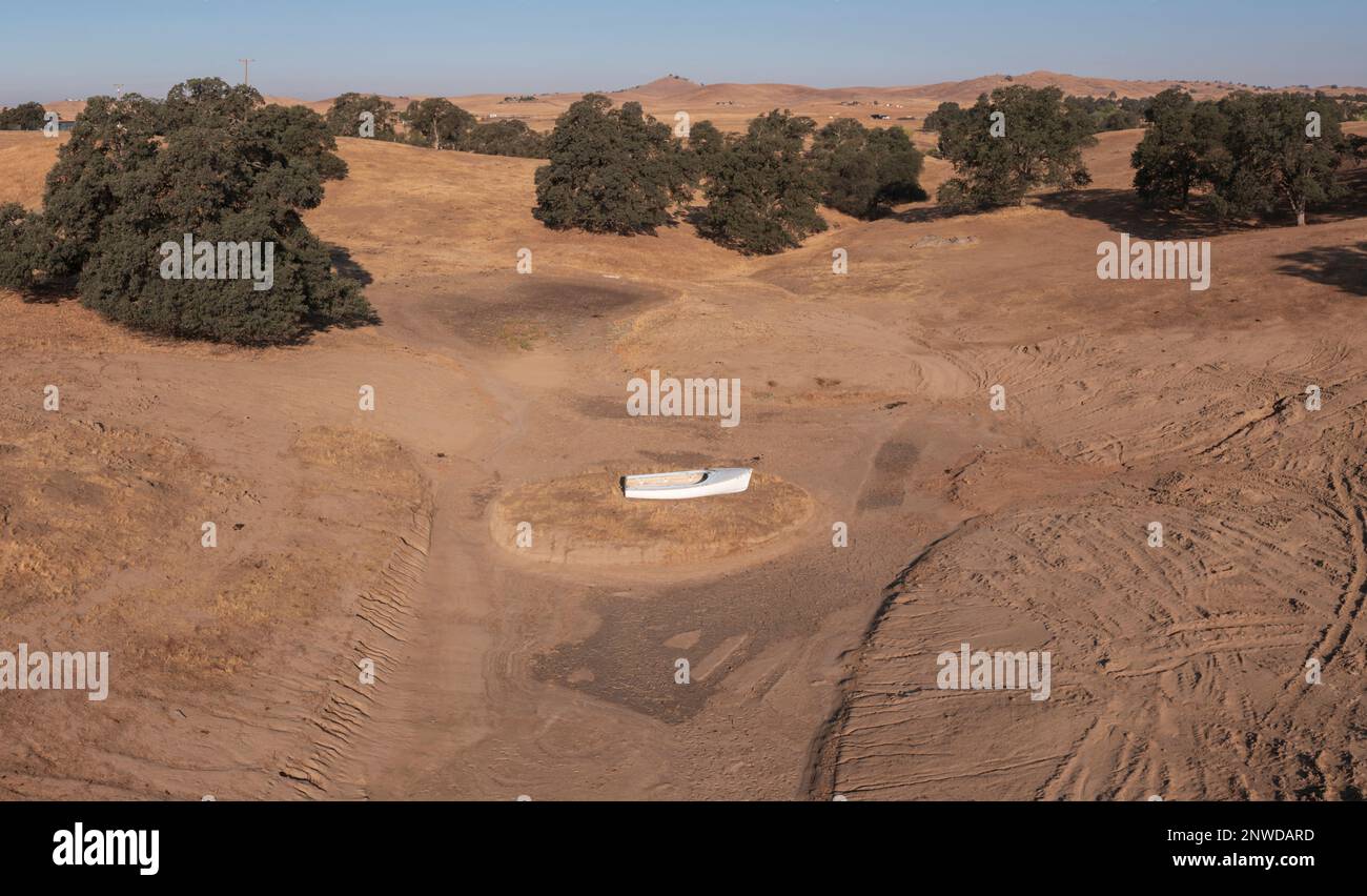 Una barca abbandonata riposa su un letto di lago asciutto vicino al lago Hensley nella valle californiana di San Joaquin, arroccata e colpita dalla siccità. Foto Stock