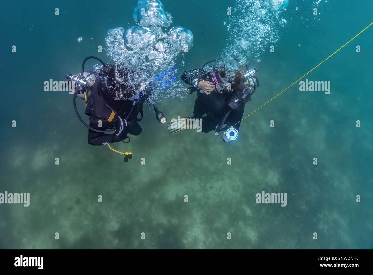 Il maestro subacqueo e l'allievo subacqueo si preparano ad ascendere dopo l'allenamento subacqueo in acque poco profonde. Attendono alla sosta ascendente per l'immersione per essere pronti per la decompressione. Foto Stock