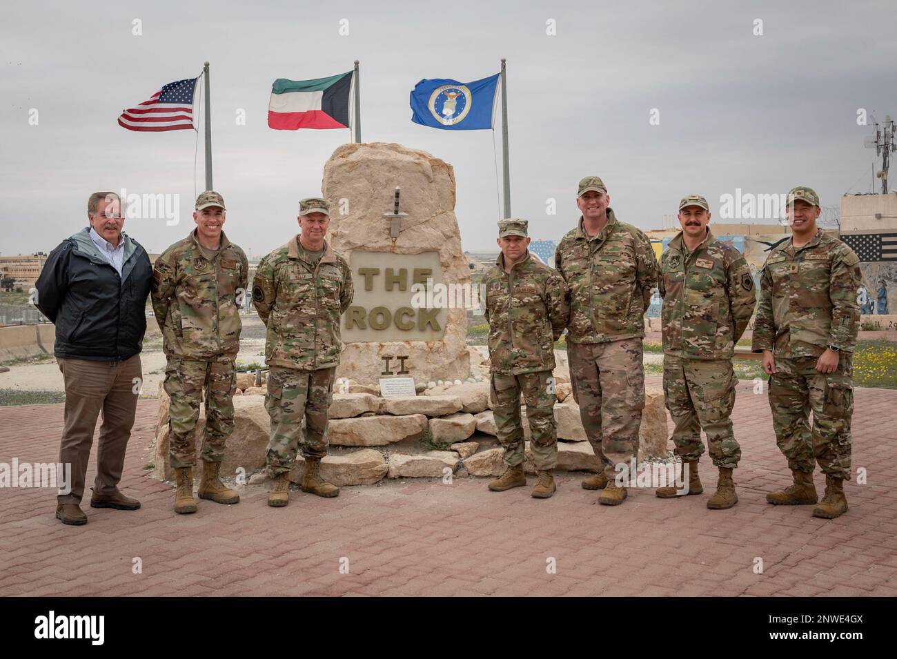 STATI UNITI Mark Kelly, comandante del comando di combattimento aereo, e il capo del comando Sgt. John Storms, ACC, posa per una foto con la leadership di 386th Air Expeditionary Wing di fronte a “The Rock” durante un tour alla base aerea di Ali al Salem, Kuwait, 15 febbraio 2023. AASAB è il governo degli Stati Uniti Il punto di accesso al teatro del comando centrale, ed è responsabile di aiutare le risorse e le capacità del progetto a entrare ulteriormente nell’area di responsabilità, mentre gli Stati Uniti rafforzano la loro presenza permanente nell’AOR. Foto Stock