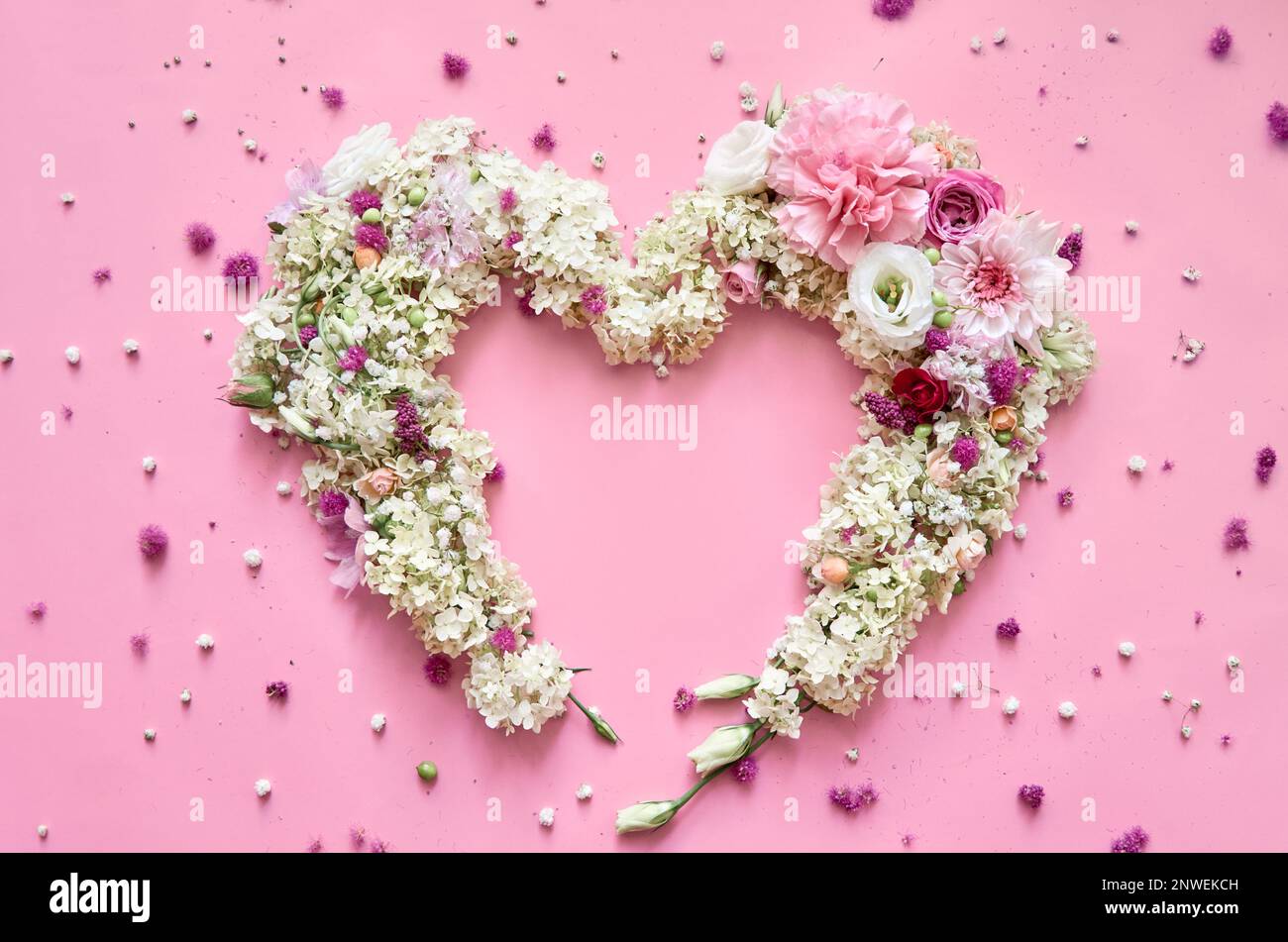 Fiori petali cuore su sfondo rosa pastello floreale. Piano di giacitura, vista dall'alto Foto Stock
