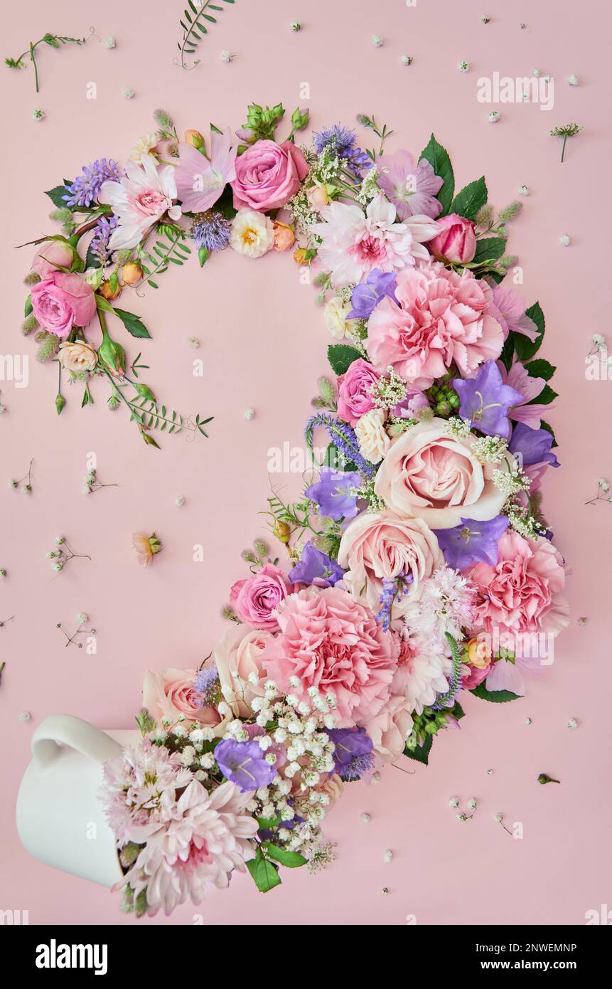 Fiori e foglie in tazza su sfondo rosa pastello floreale. Giacitura piatta, verticale Foto Stock
