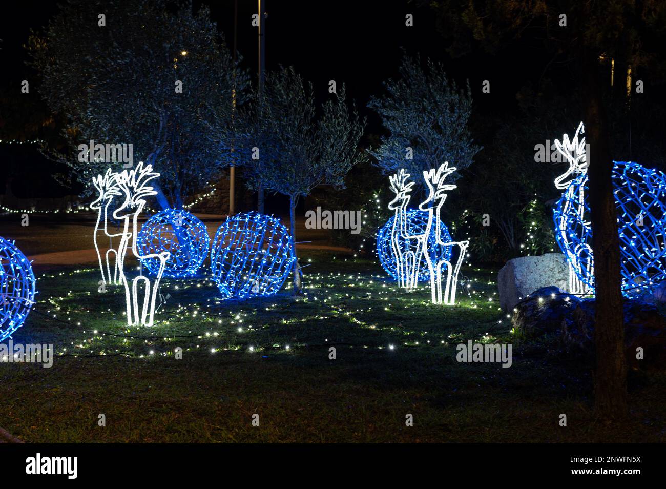Décorations lumineuses de Noël, rennes blancs et boules bleues sur un tapis d'herbe Foto Stock