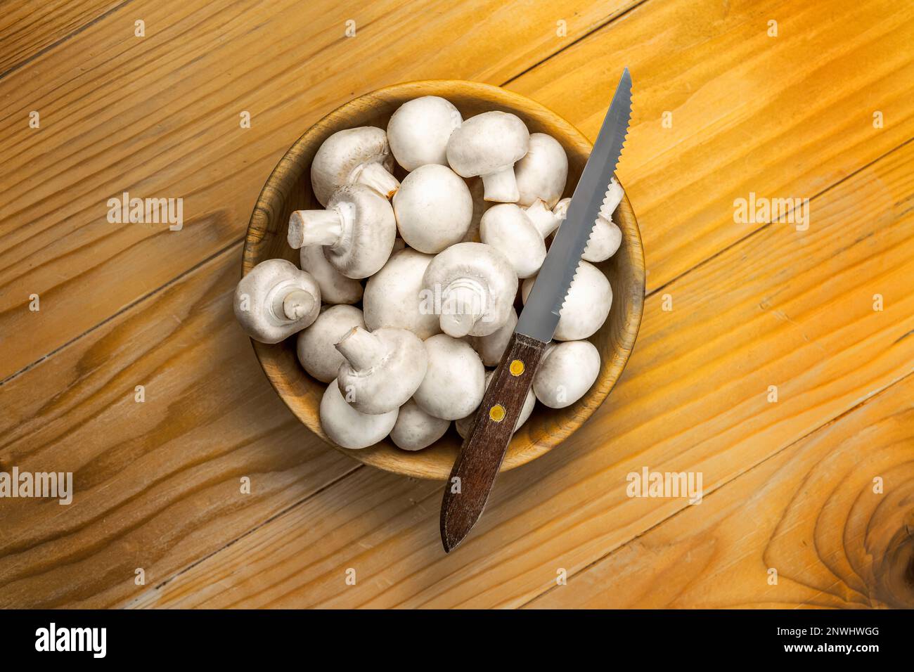 Funghi bianchi freschi champignon in ciotola di legno marrone su sfondo tavolo di legno Foto Stock