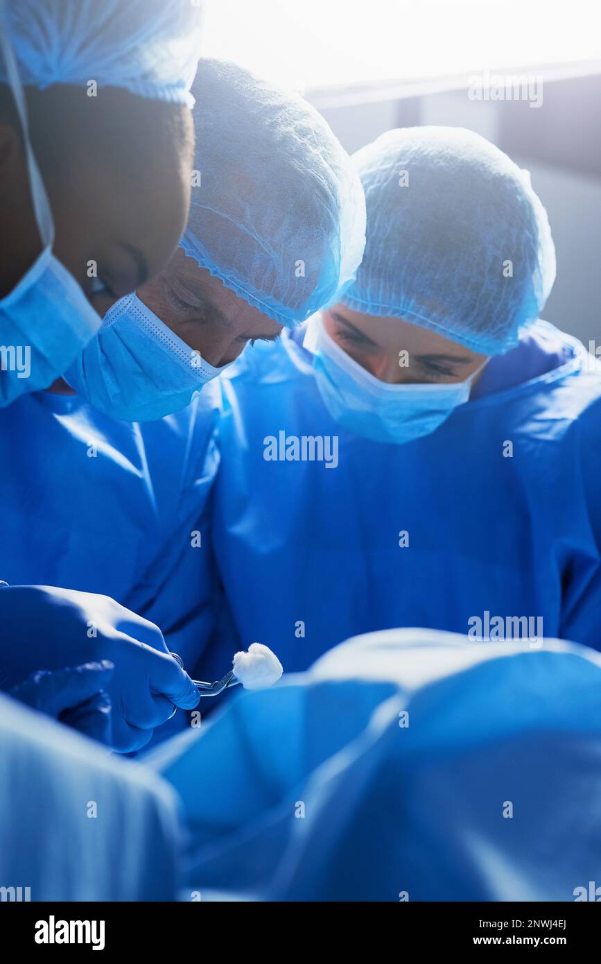 Focalizzato sulla procedura. Shot di gruppo di chirurghi che lavorano su un paziente in una sala operatoria. Foto Stock
