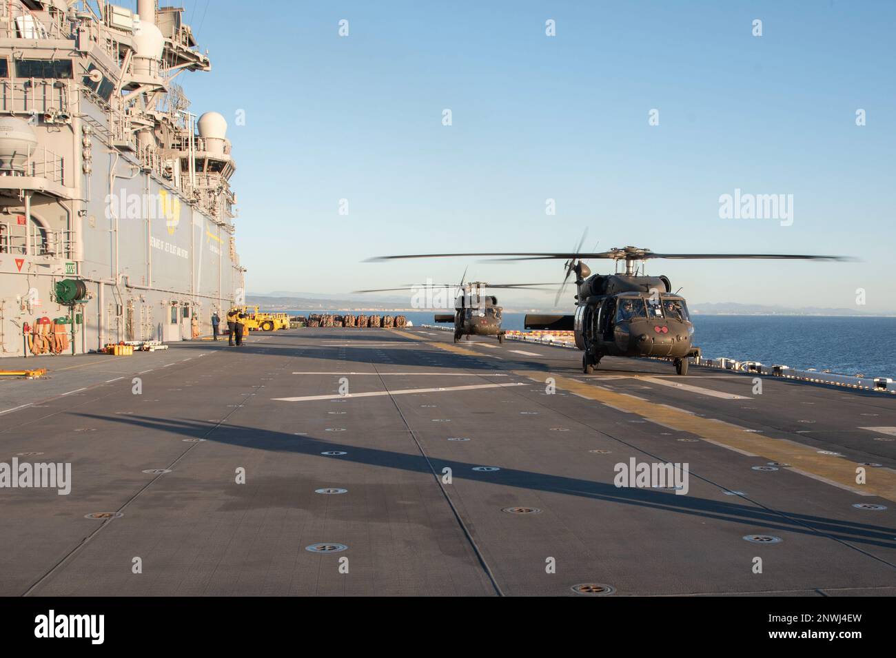 230124-N-XN177-2011 OCEANO PACIFICO (24 GENNAIO 2023) – STATI UNITI Esercito UH-60 elicotteri Black Hawk assegnati alla Brigata dell'Aviazione di combattimento 16th si preparano a decollare dal portatore d'assalto anfibio USS Tripoli (LHA 7) 24 gennaio 2023. Tripoli sta conducendo operazioni di routine nella U.S. 3rd Fleet. Foto Stock
