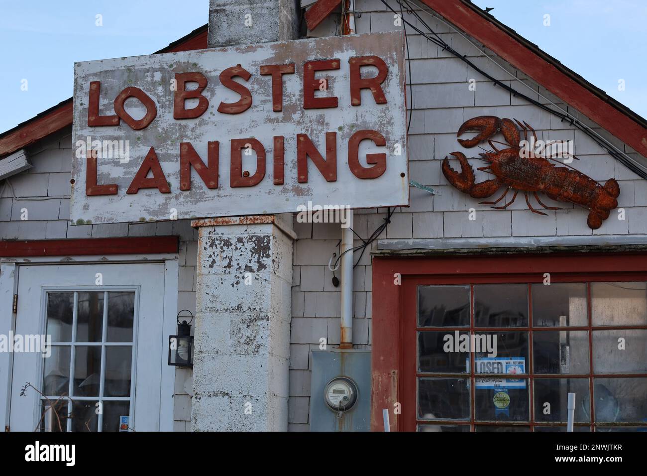 Primo piano dell'esterno di Lobster Landing a Clinton, Connecticut, USA. La foto mostra un cartello, un'aragosta metallica e la parte superiore di una porta e di una finestra. Foto Stock