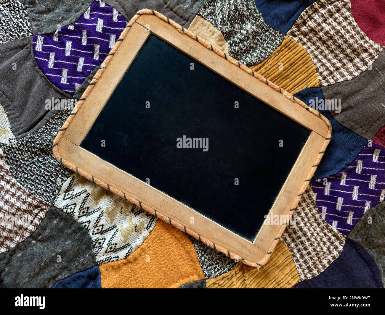 Mano tenuta lavagna bianca su viola oro vintage pazzo tessuto trapunta ha spazio per il testo, messaggio di pubblicità segno. Coperta di fondo è fatta a mano. Foto Stock