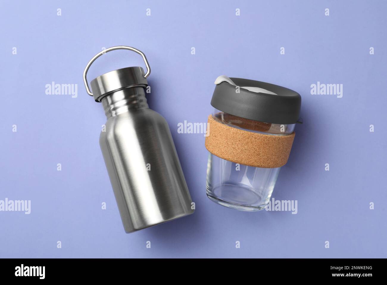 Bottiglia e tazza eco-friendly su fondo lavanda, piatto. Consumo consapevole Foto Stock