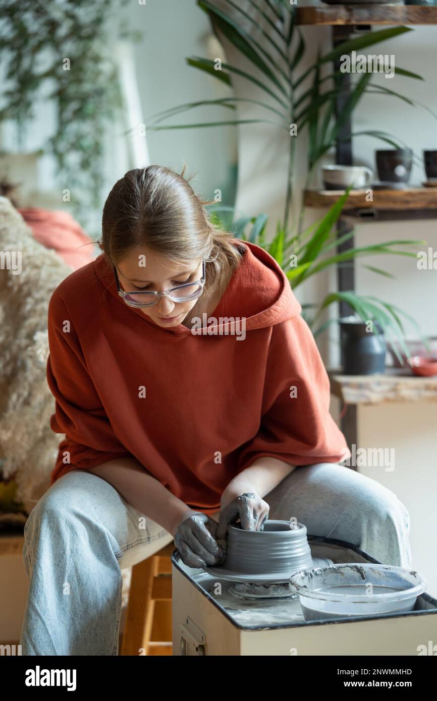 Professionista entusiasta lavori artificiere donna si siede vicino ceramisti ruota fare brocche da argilla Foto Stock