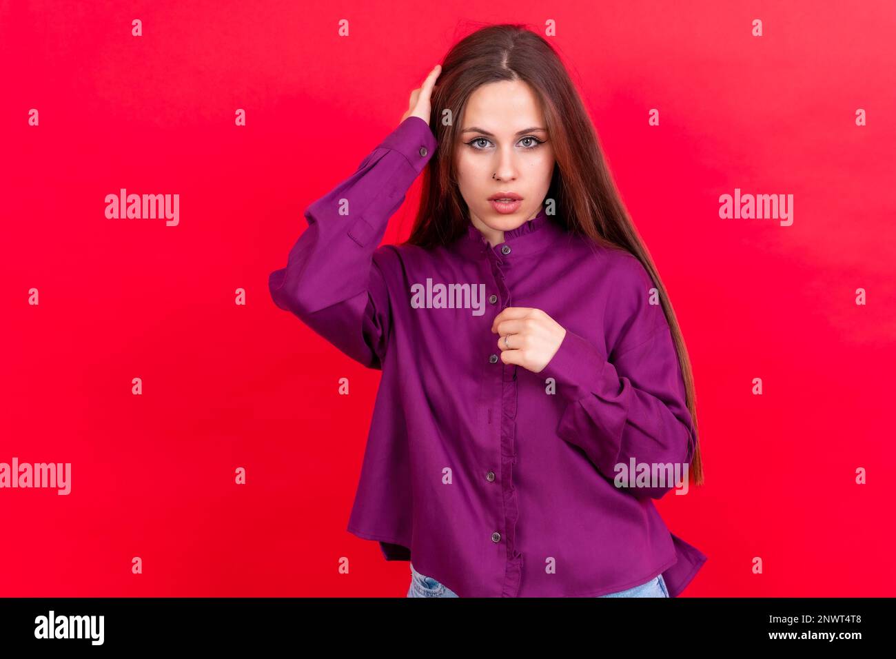 Primo piano ritratto di giovane donna caucasica in camicia viola isolato su sfondo rosso studio Foto Stock