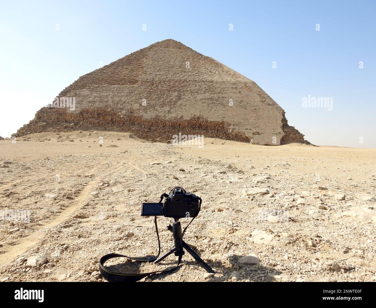 Una fotocamera reflex digitale su un cavalletto che fotografa la piramide piegata del re Sneferu, Un esempio unico di sviluppo piramidale iniziale in Egitto situato a da Foto Stock