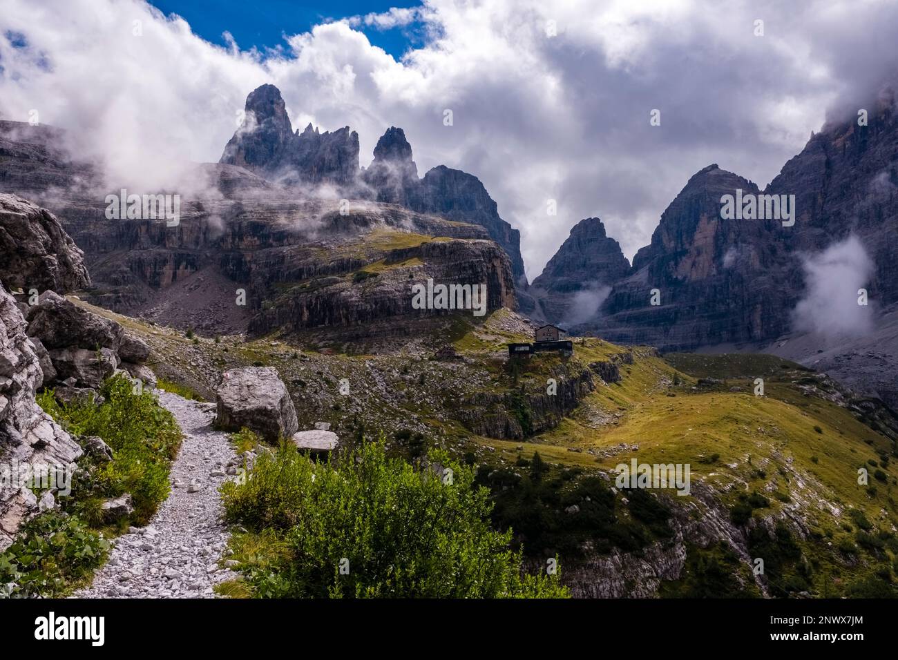 Un sentiero escursionistico nelle Dolomiti di Brenta che conduce al rifugio Maria e Alberto al Brentei, cime in lontananza parzialmente avvolte da nuvole Foto Stock