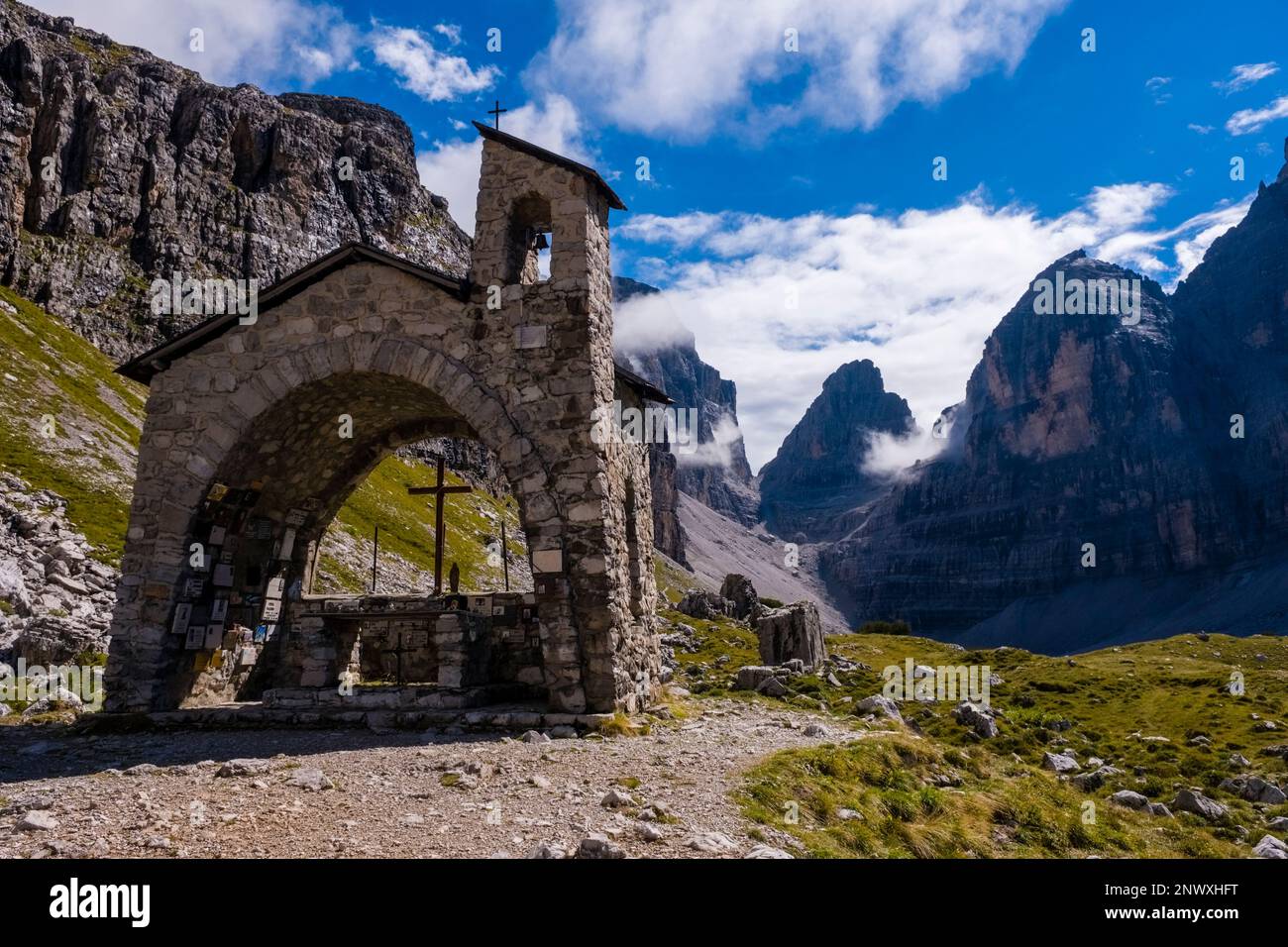 La piccola cappella vicino al rifugio Maria e Alberto al Brentei nelle Dolomiti di Brenta, il valico bocca di Brenta in lontananza. Foto Stock