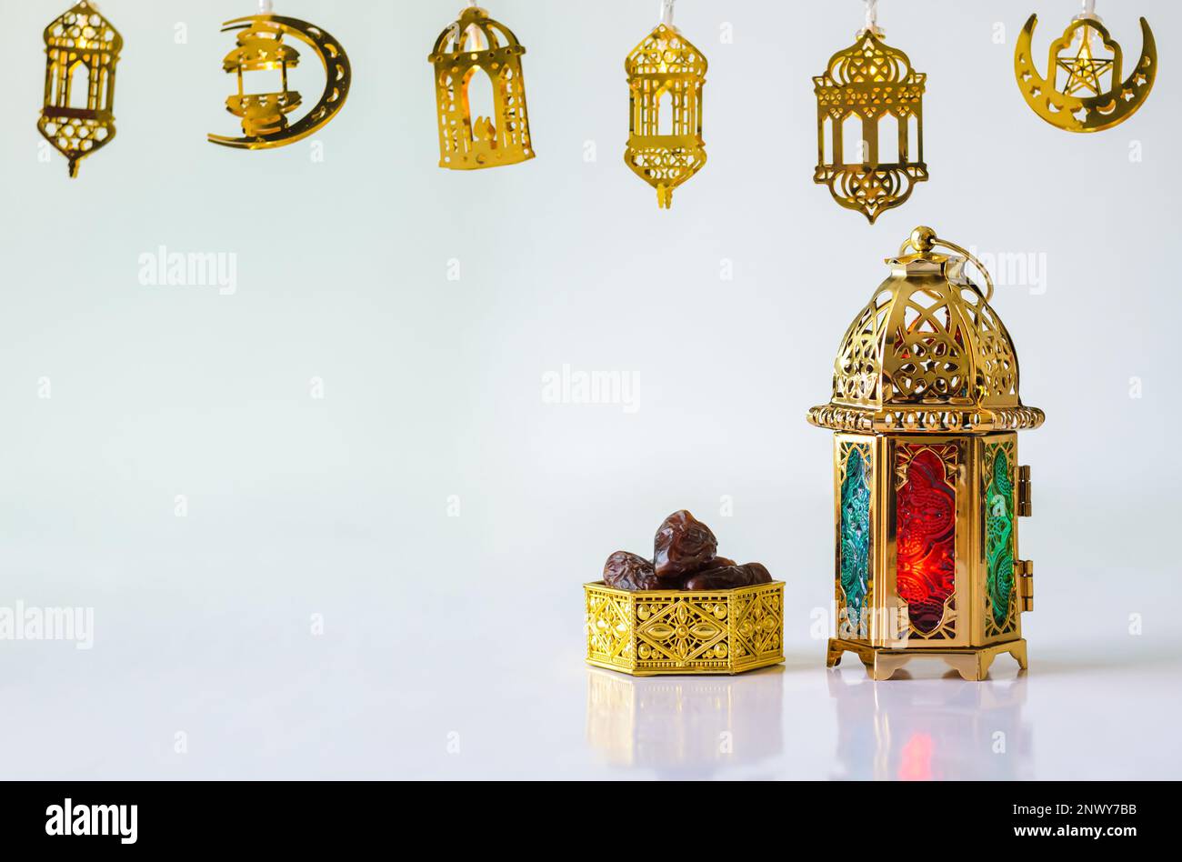 Lanterna d'oro con datteri di frutta su sfondo bianco con luci decorate per la festa musulmana del mese santo di Ramadan Kareem. Foto Stock