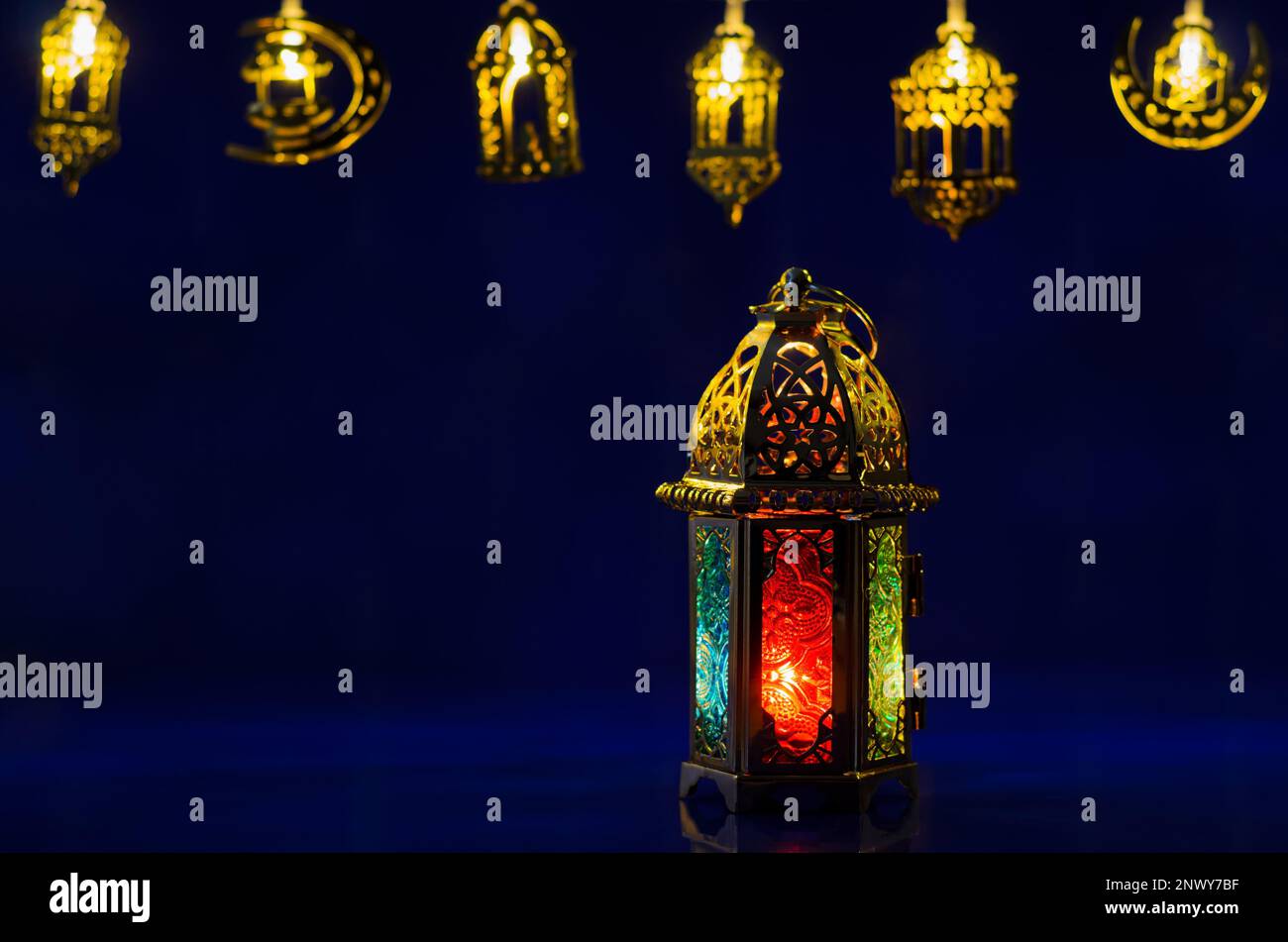 La lanterna dorata si accende su sfondo blu scuro con luci decorate per la festa musulmana del mese santo di Ramadan Kareem. Foto Stock