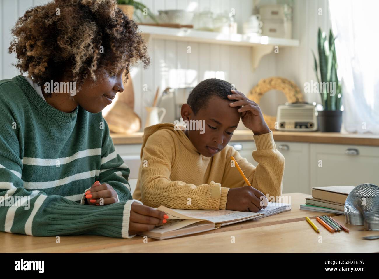 Caring African American mamma sostegno pensivo scolaro adottato figlio con l'incarico di istruzione a casa Foto Stock