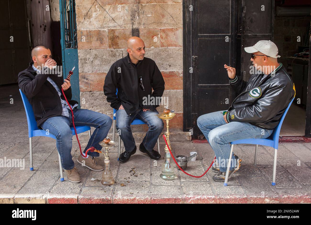 Scena di strada, arabo uomini fumatori Nargila tubo di acqua nella zona del mercato del Muristan chiamato Suq Aftimos, la Città Vecchia di Gerusalemme, Israele. Foto Stock