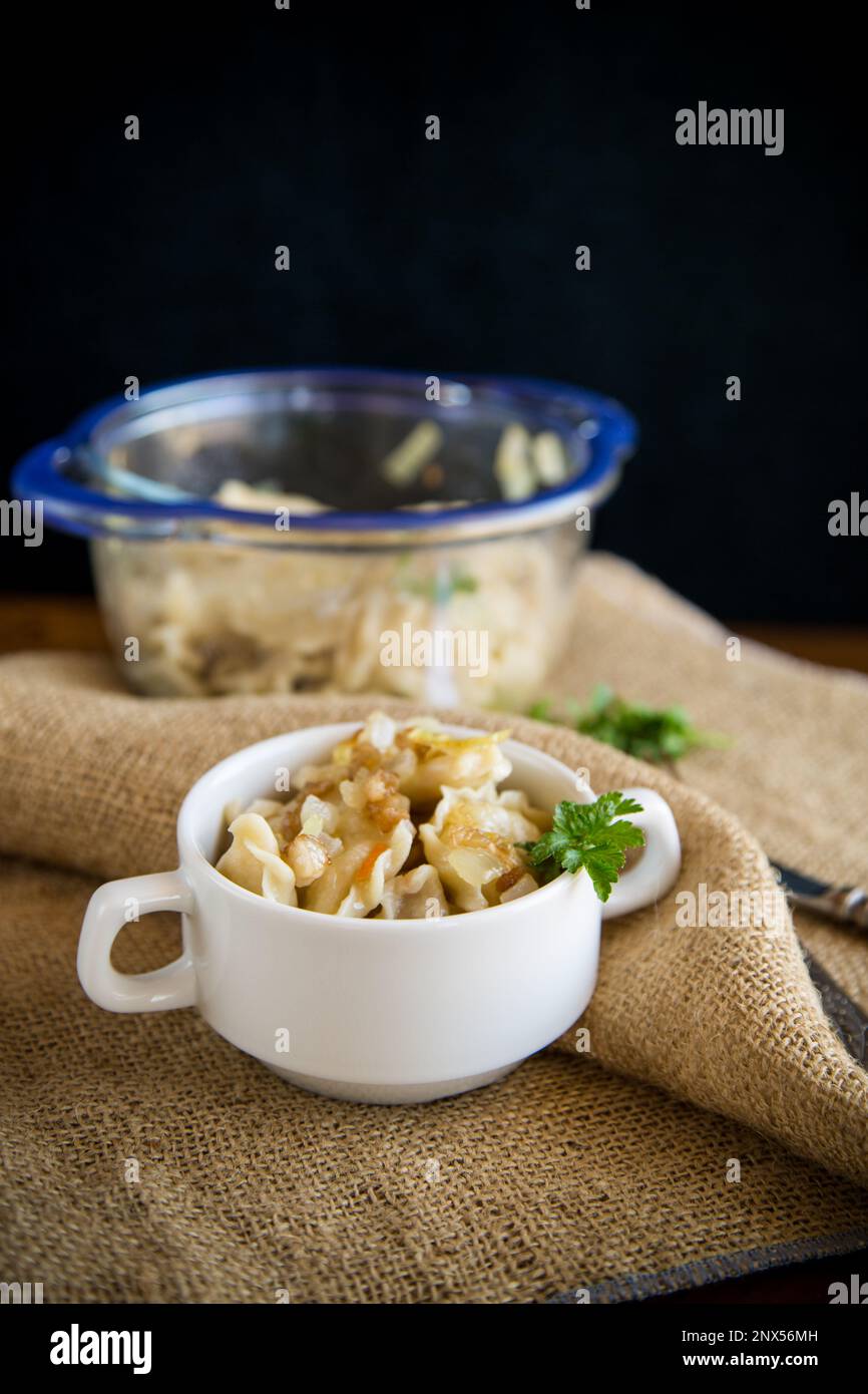 gnocchi cotti con patate e cipolle fritte, in una ciotola su un tavolo di legno. Foto Stock