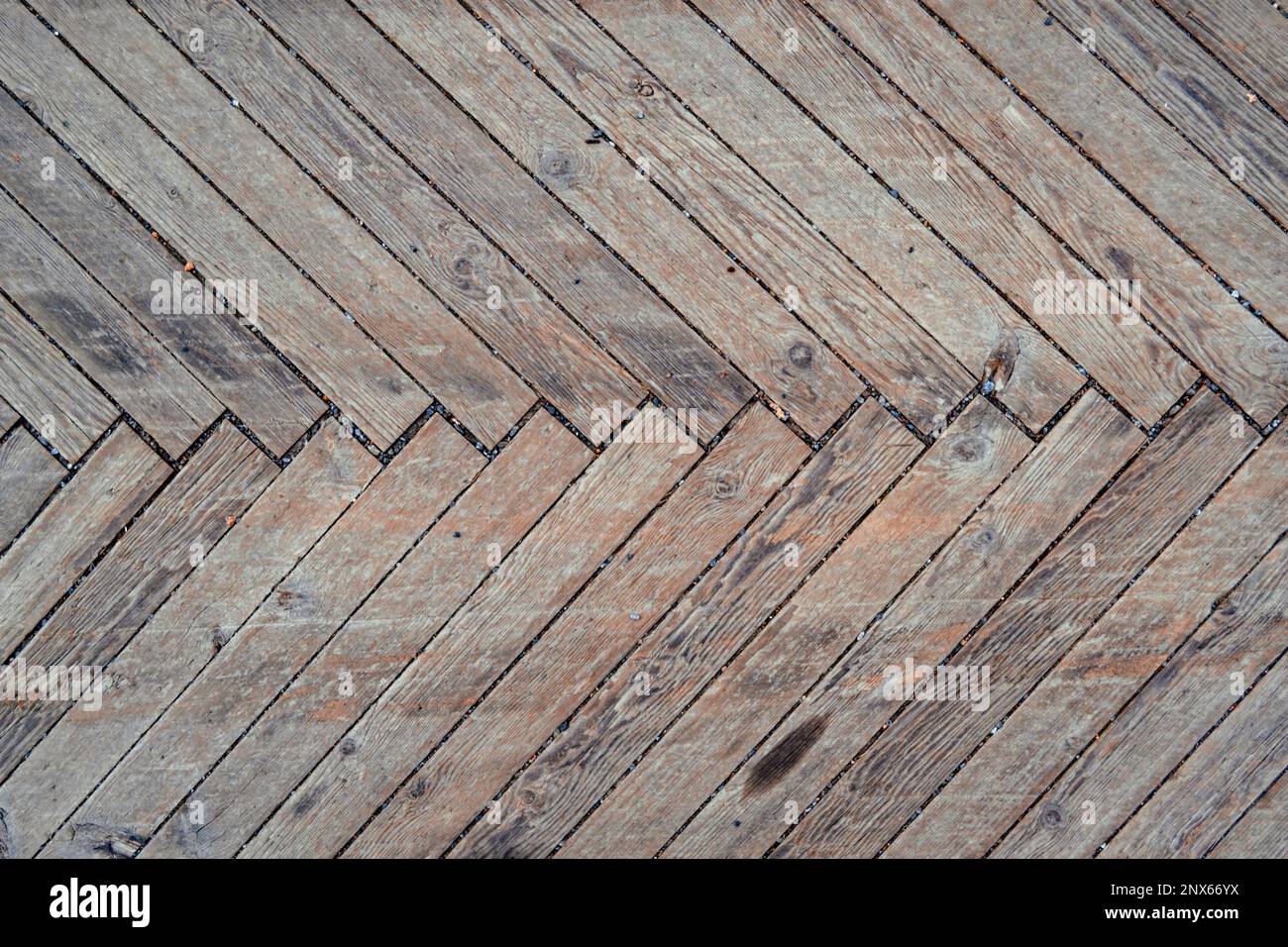 Vecchio pavimento in terrazza in legno con pavimento a spina di pesce. Texture di sfondo. Foto Stock