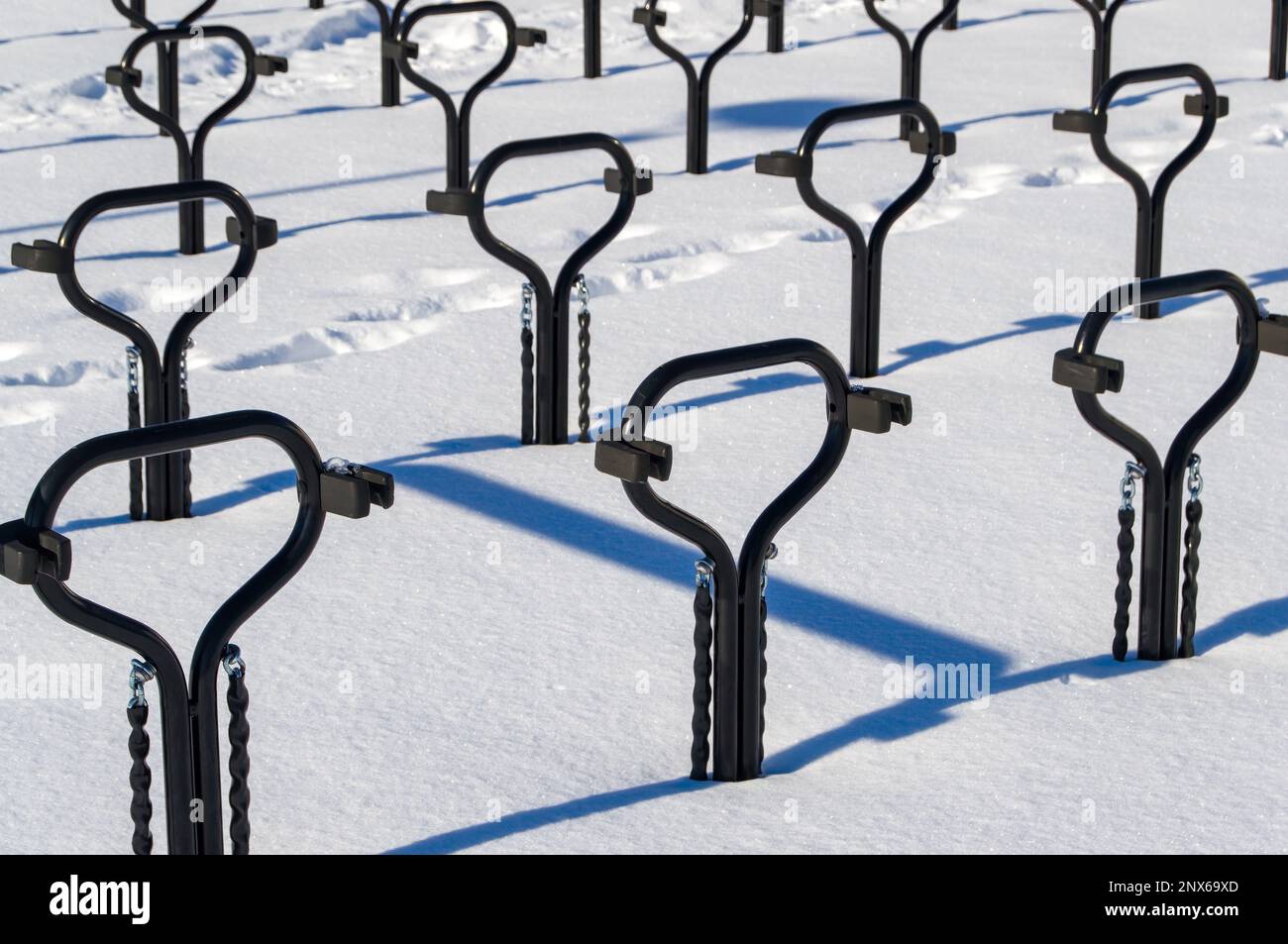 Portabiciclette in metallo nero. La foto è stata scattata in una giornata invernale di sole. Rack proietta ombre nella neve. Foto Stock
