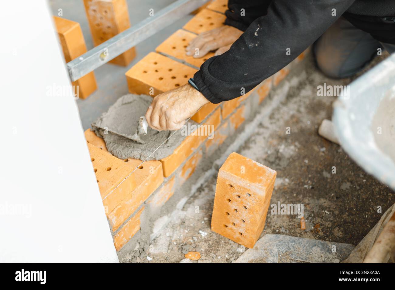 mano che ricopre il muro di mattoni con cemento e cazzuola Foto Stock