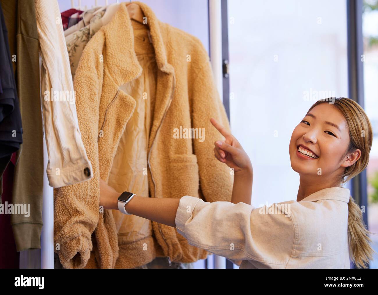 Shopping scelta, ritratto e donna asiatica guardando le vendite di vendita e sconto vestiti in un negozio. Moda, sorriso e cliente femminile giapponese con un Foto Stock