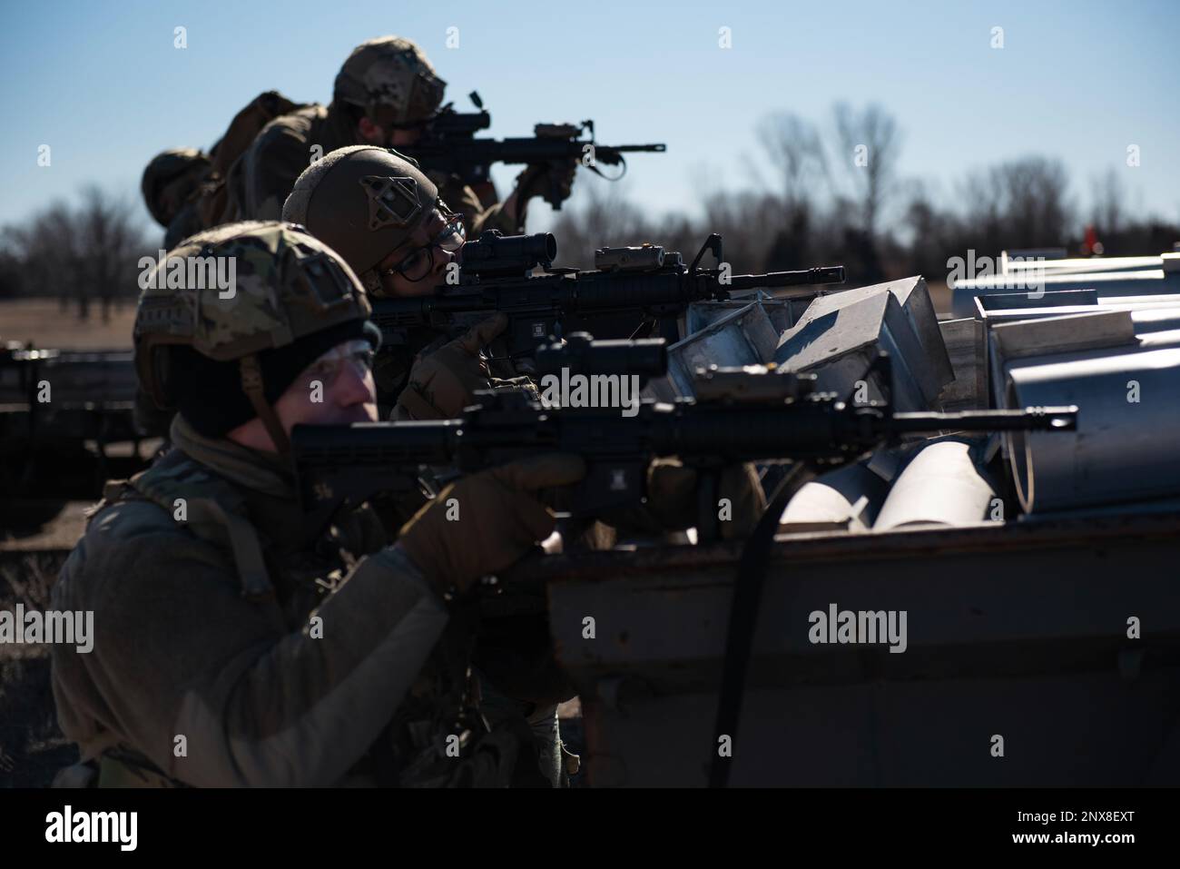 Staff Sgt. Daniel McGinnis, front, 22nd Security Forces Squadron Patrollman, Senior Airman Alexis Williams, middle, 22nd SFS Flight leader, e altri difensori si inginocchiano dietro una barricata durante l'allenamento congiunto alla McConnell Air Force base, Kansas, 3 febbraio 2023. Insieme agli approcci tattici e ai ritiri per pulire gli edifici, gli Airmen si sono allenati con gli Stati Uniti Soldati dell'esercito dal battaglione dell'elicottero d'assalto del 3rd, reggimento dell'aviazione del 1st da Fort Riley, Kansas, per praticare decolli tattici e atterraggi in un UH-60 Blackhawk. Foto Stock