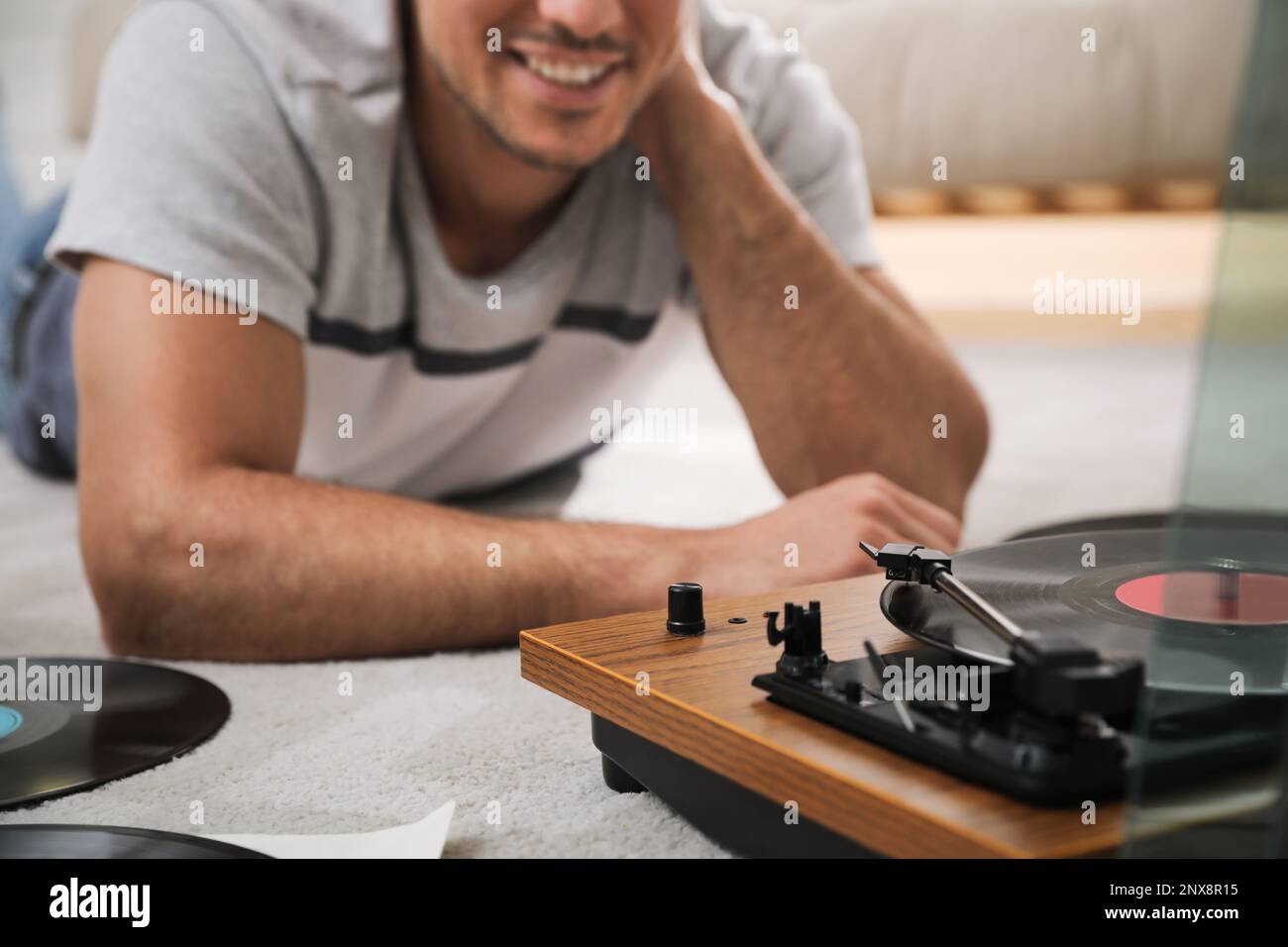 Uomo felice che usa il giradischi a casa, primo piano Foto Stock